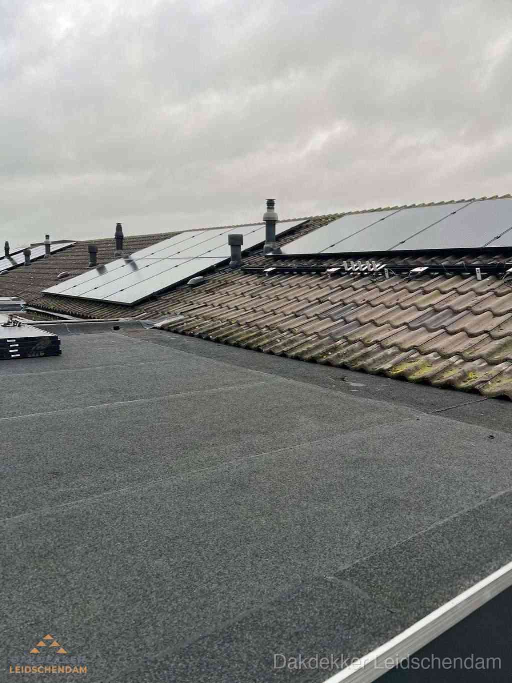 Plat dak inspectie met bitumen bedekking naast schuin pannendak in Leidschendam