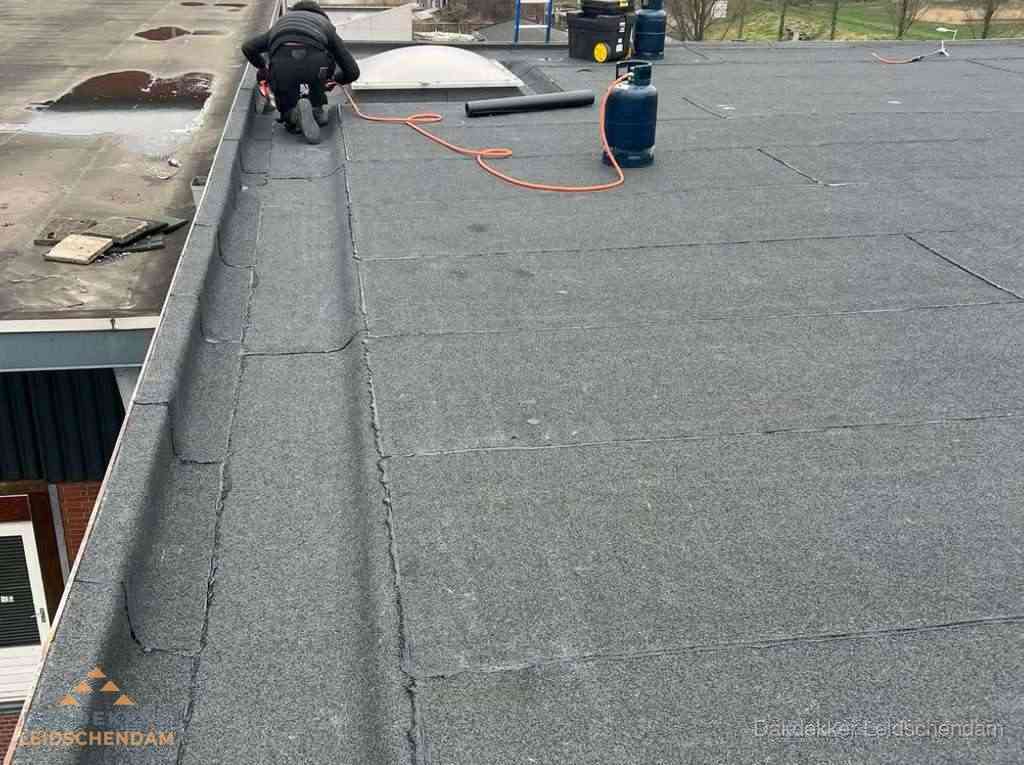 Dakdekker repareert bitumen dakbedekking op groot plat dak in Leidschendam