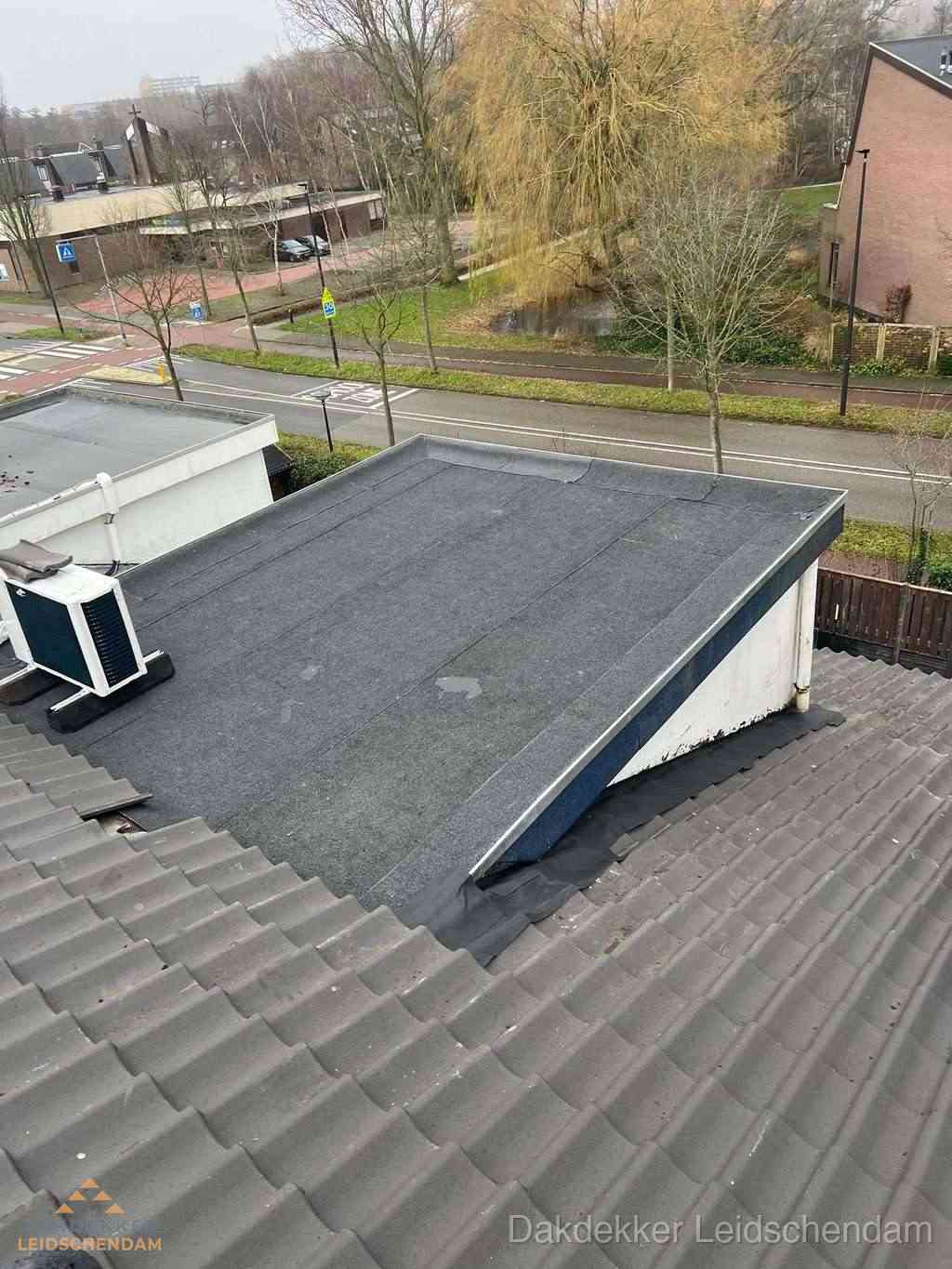 Plat dak met bitumen dakbedekking naast schuin pannendak in Leidschendam