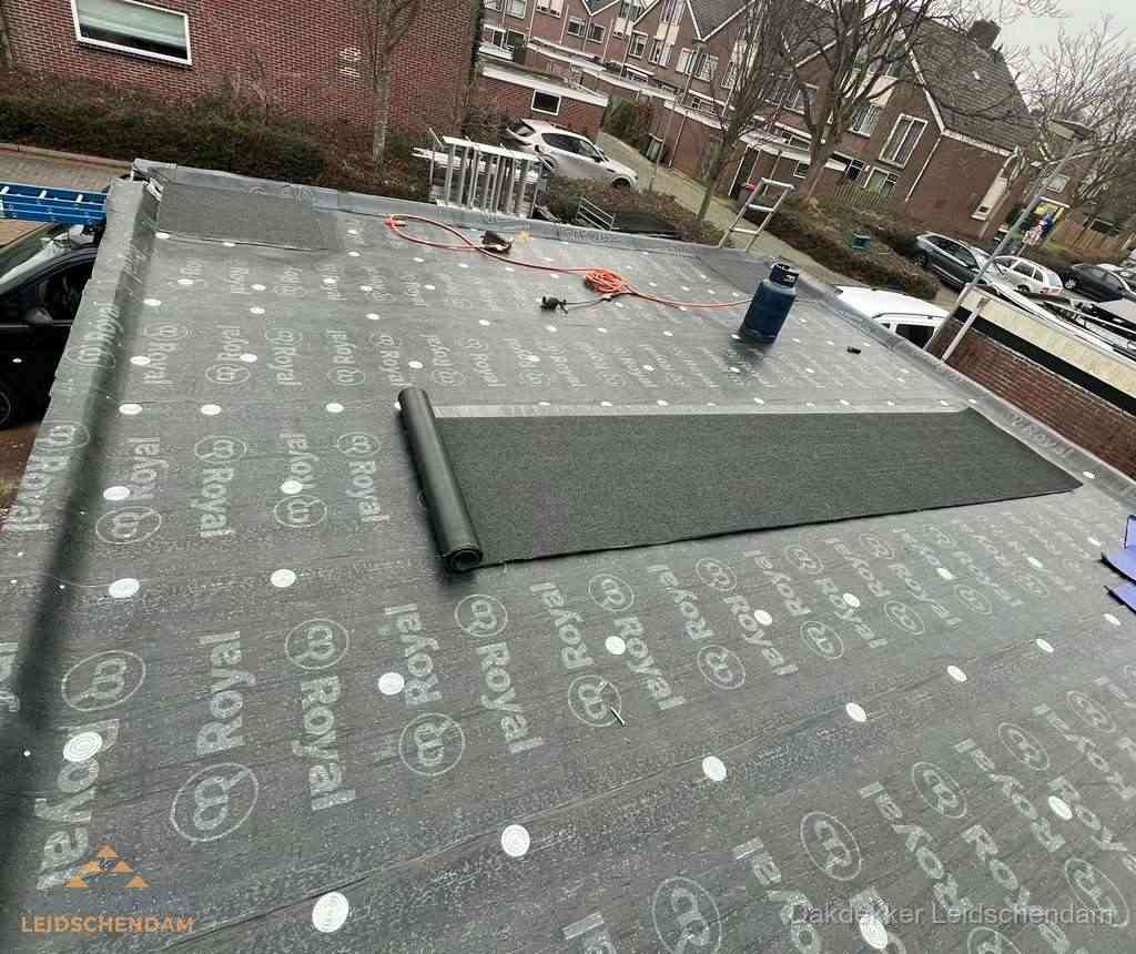 Dakdekker aan het werk met gasbrander op plat bitumen dak in Leidschendam